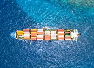 An aerial view of a cargo ship in the ocean by Bent Van Aeken courtesy of Unsplash.