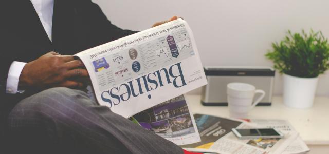 person sitting near table holding newspaper by Adeolu Eletu courtesy of Unsplash.