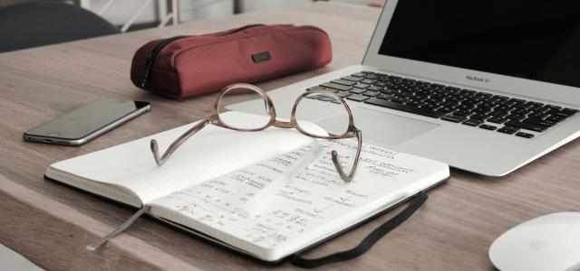 eyeglasses on book beside laptop by Dan Dimmock courtesy of Unsplash.